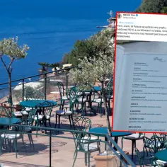 Menu z cenami pizzy w restauracji nad morzem we Włoszech, z widokiem na błękitne morze.